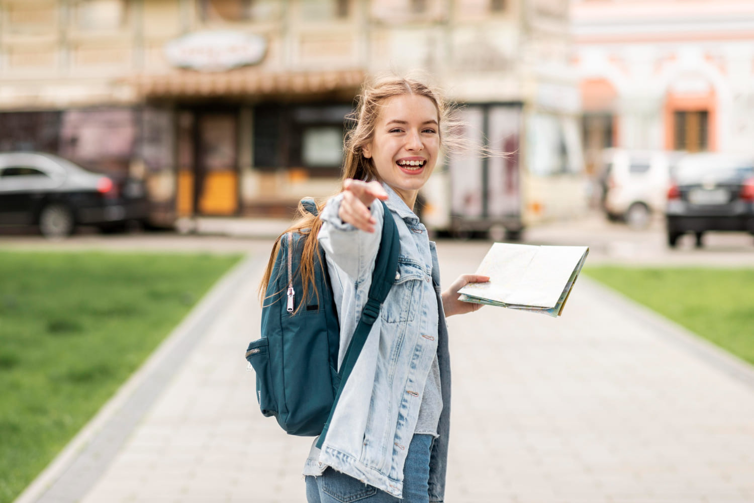 Study in Scotland: Confident traveling girl pointing with her finger and holding map, ready to explore with confidence